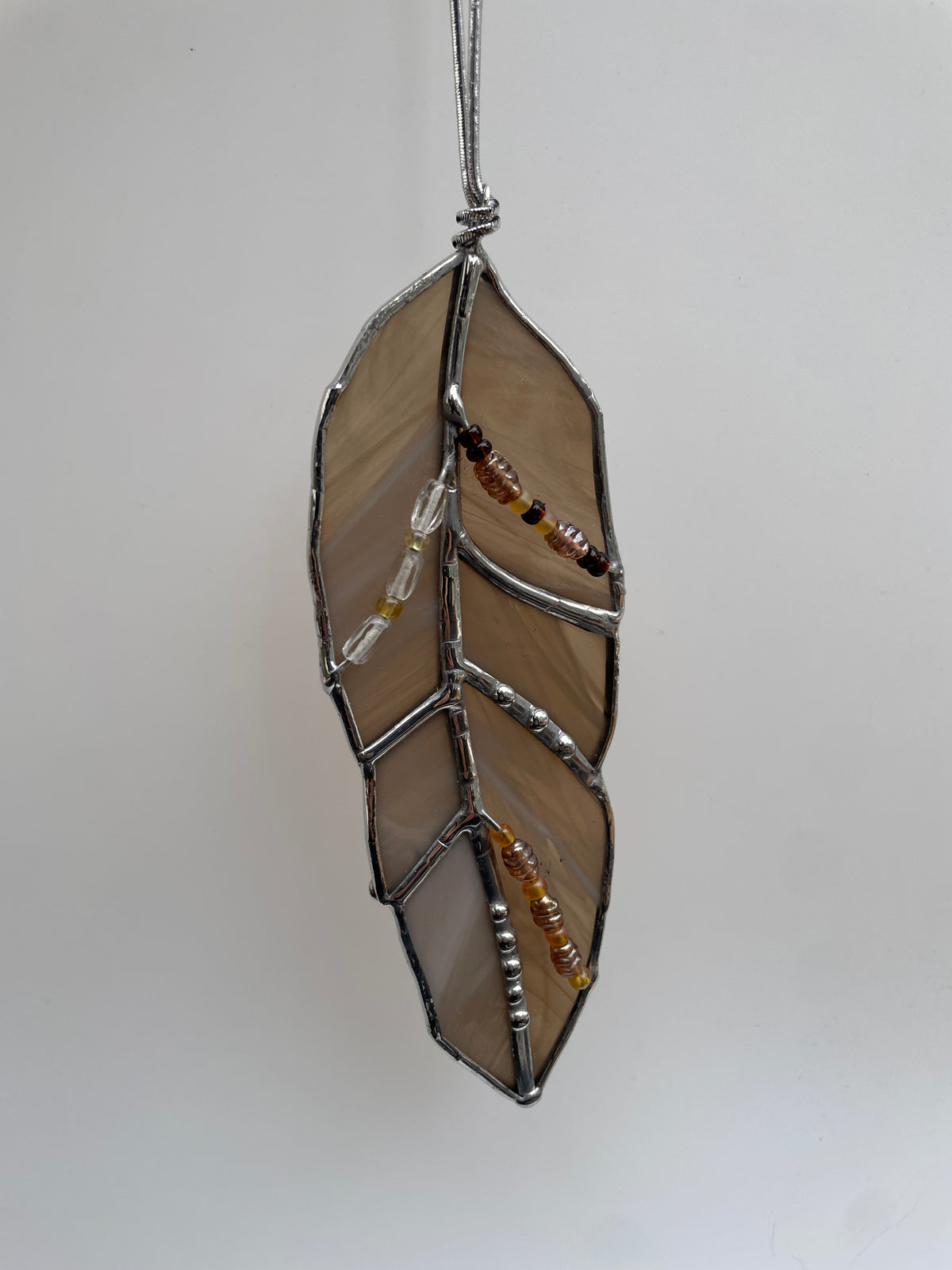 Bronze stained glass feather with wispy white glass and decorative solder detail