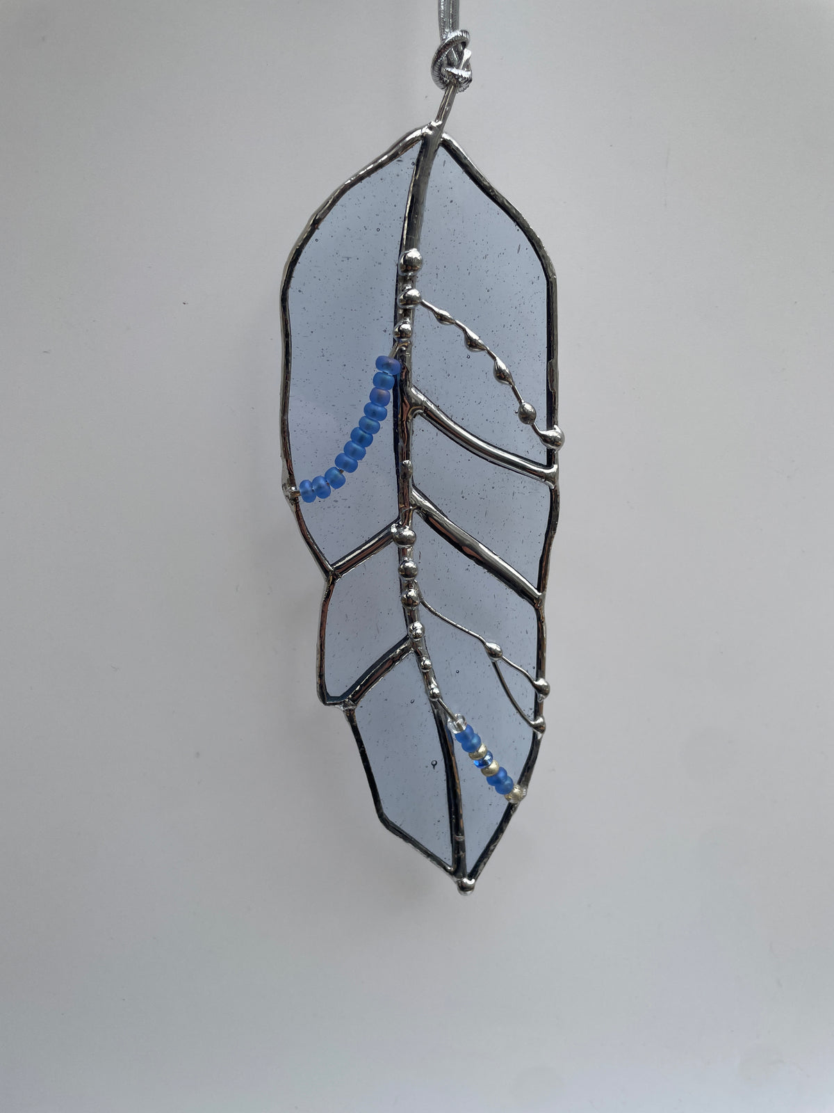 Light blue handcrafted stained glass feather with decorative solder detail