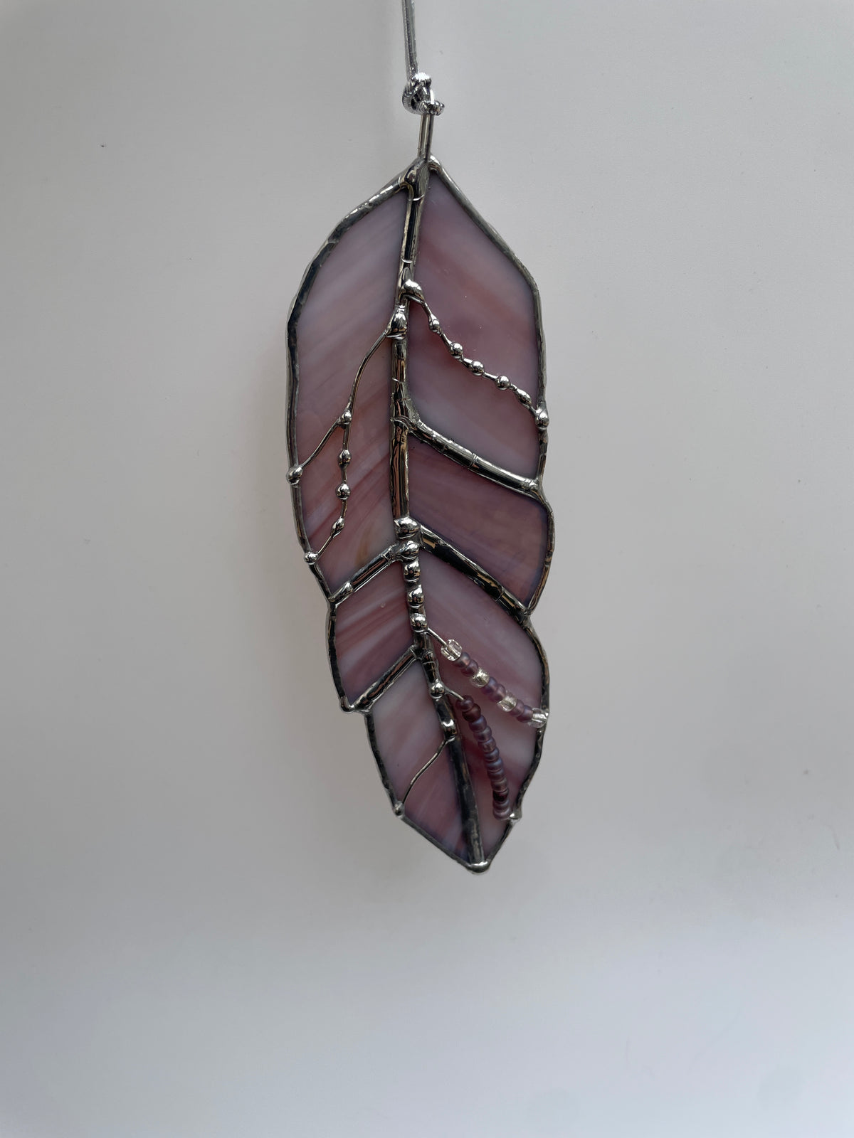 Purple, white, and amber-granite stained glass feather handcrafted by Christina Knightly